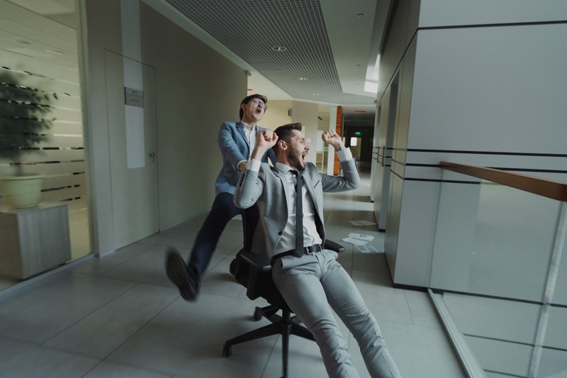 Zwei Personen lachen ausgelassen in einem Büroflur.